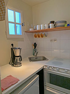 Inside kitchenette with dishes, coffee maker, fridge, and sink. 