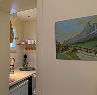 Inside kitchenette with dishes, coffee maker, fridge, and sink.  Mountain painting.