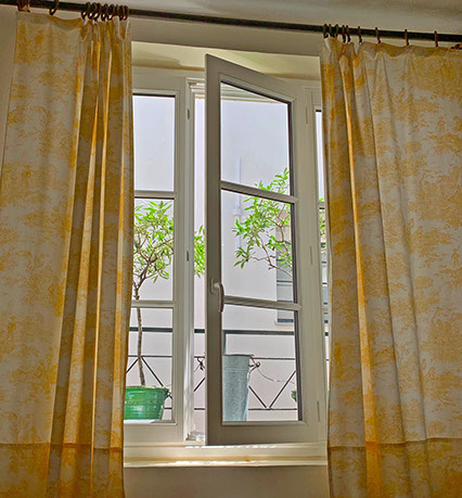 New living room window with toile de Jouy curtains and olive trees beyond.
